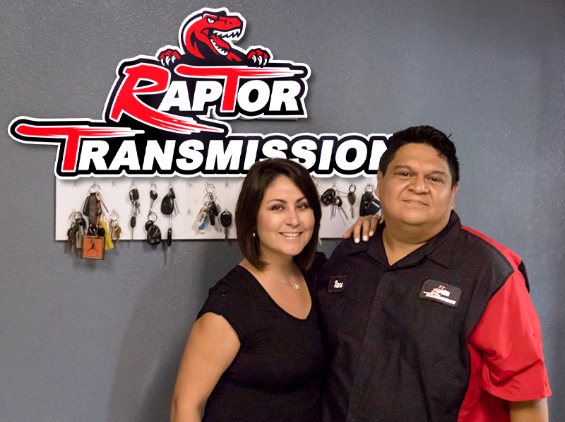 A man and a woman pose in front of a raptor transmission sign