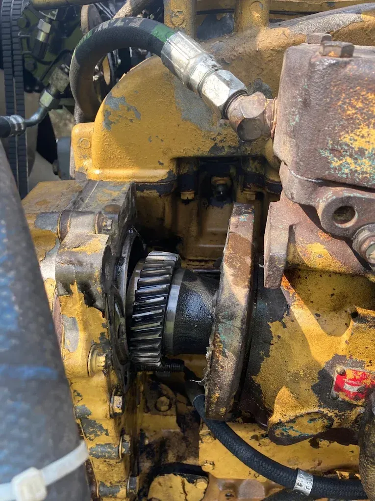 A close up of a yellow engine with a hose attached to it.