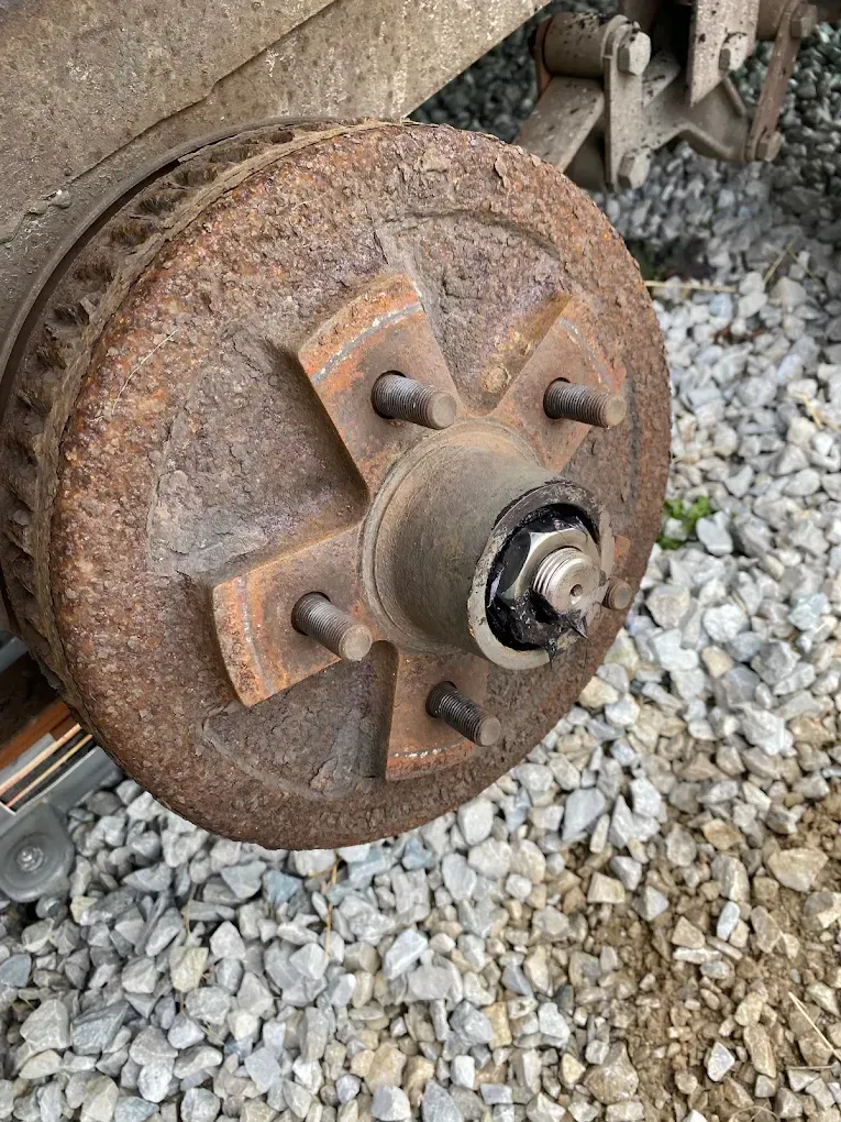 A rusty brake drum is sitting on top of a pile of gravel.