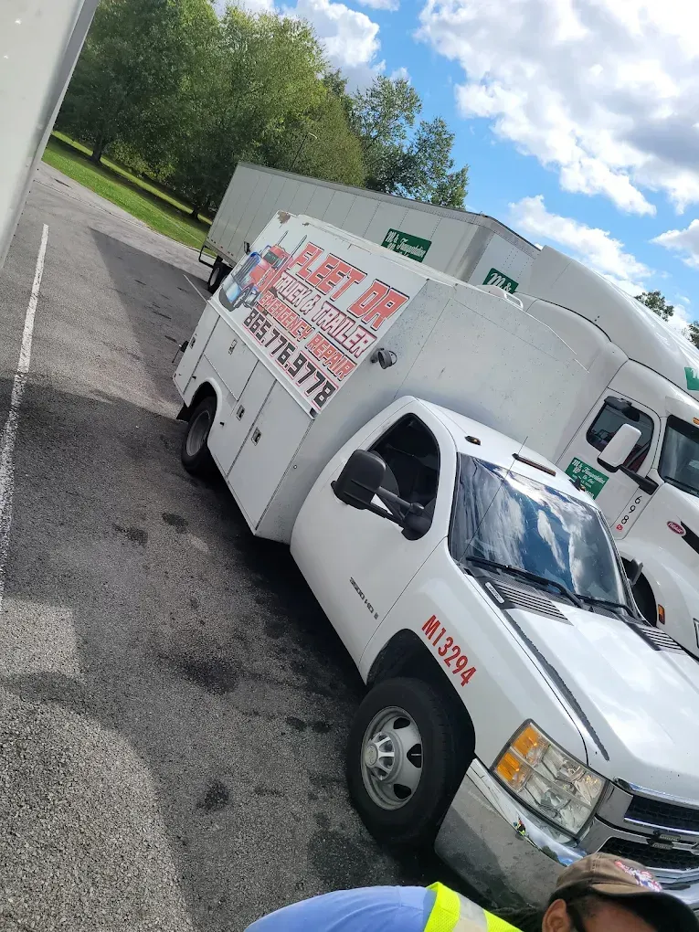 A man is standing in front of a row of moving trucks.