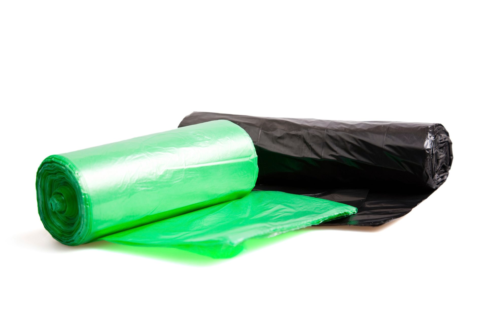 Un rollo de bolsas de basura verdes y un rollo de bolsas de basura negras sobre un fondo blanco.