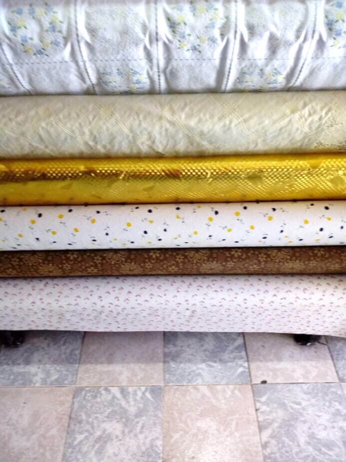 Una pila de telas de diferentes colores sobre un suelo de baldosas.