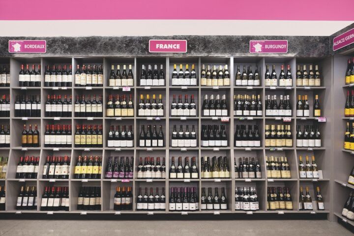 Wine bottles on shelves organized by region.