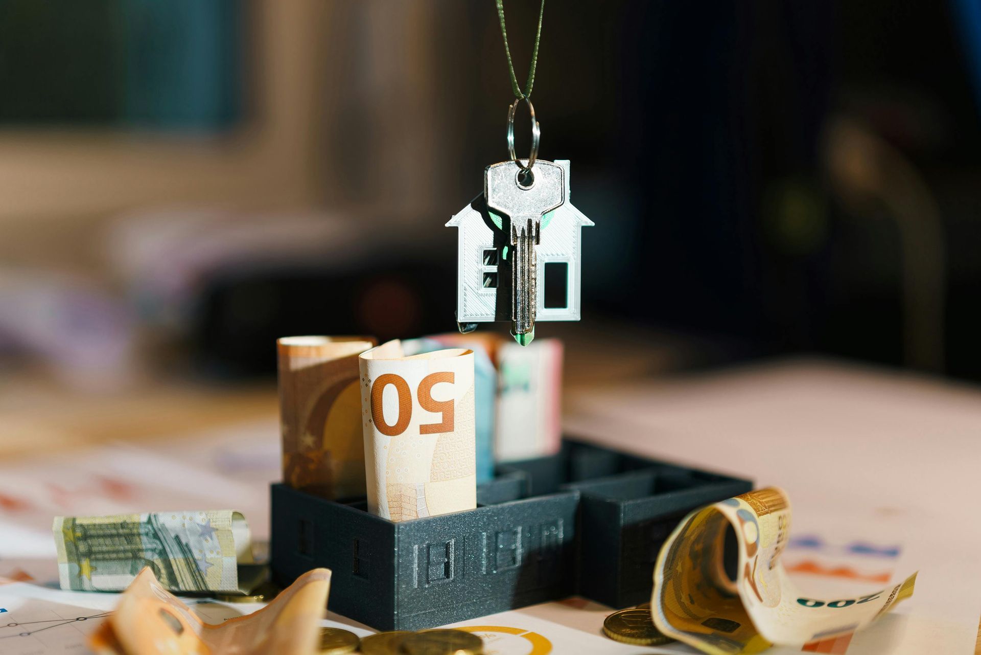 Money sitting on top of a table with a house key hanging from it.