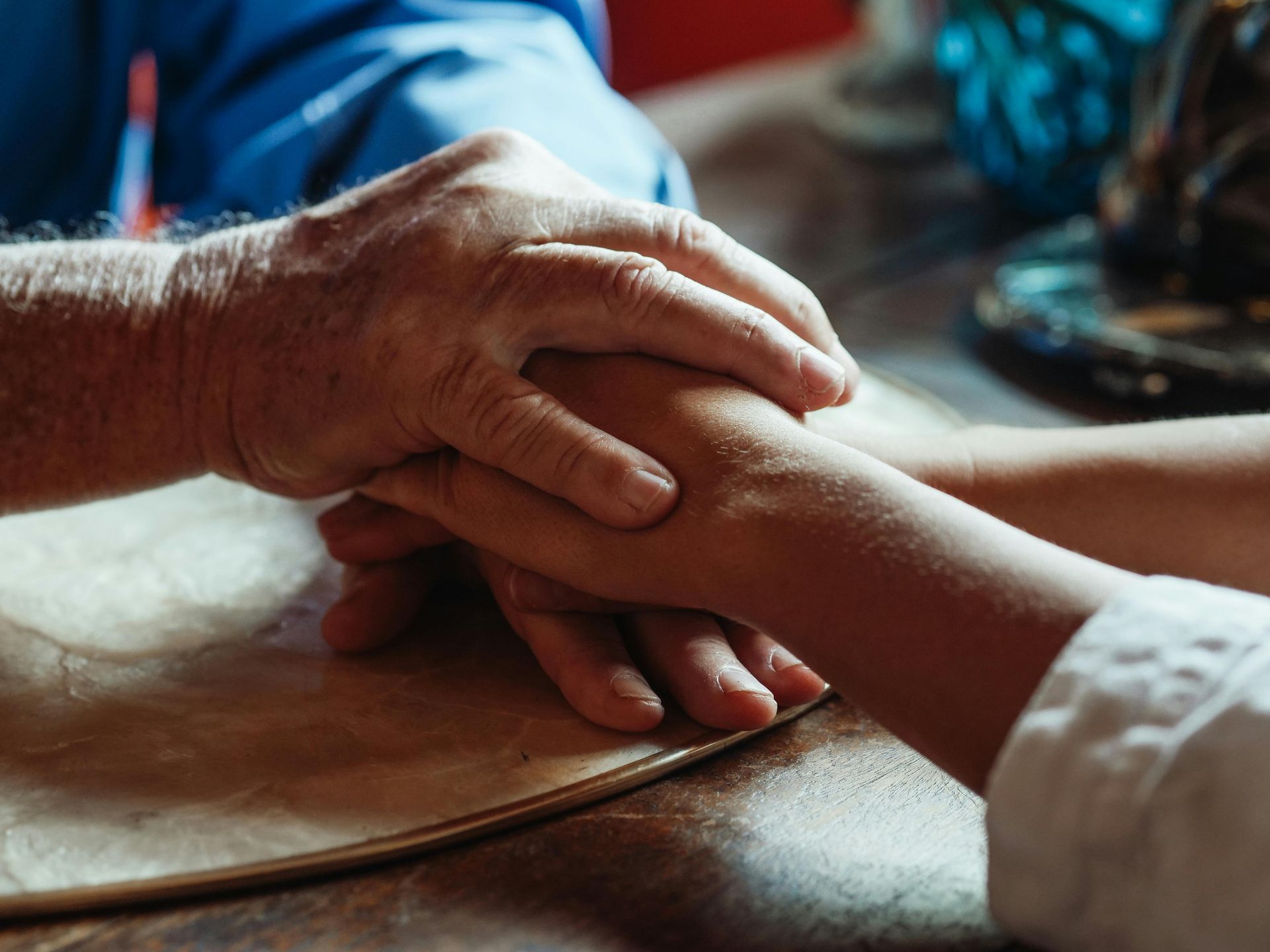 A person is holding another person 's hand on a table.