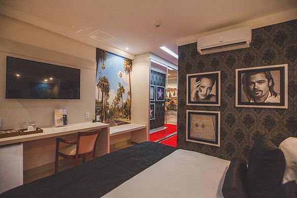 Um quarto de hotel com uma cama, cadeira, escrivaninha e televisão.