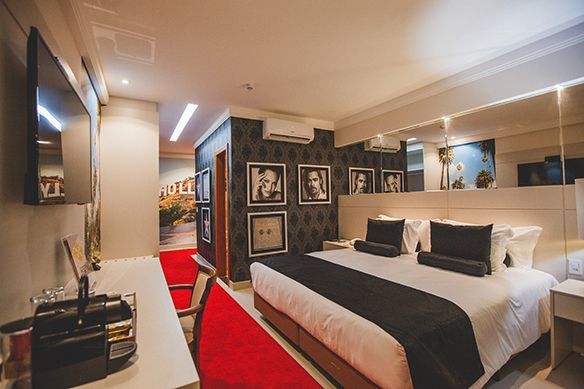 Um quarto de hotel com uma cama, mesa de cabeceira, lâmpadas e espelhos.