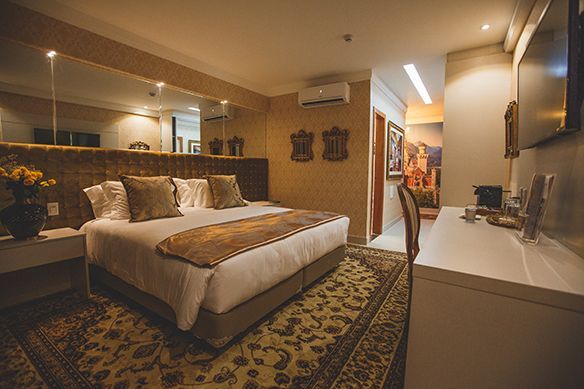 Um quarto de hotel com uma cama king size, cadeira, escrivaninha e televisão.