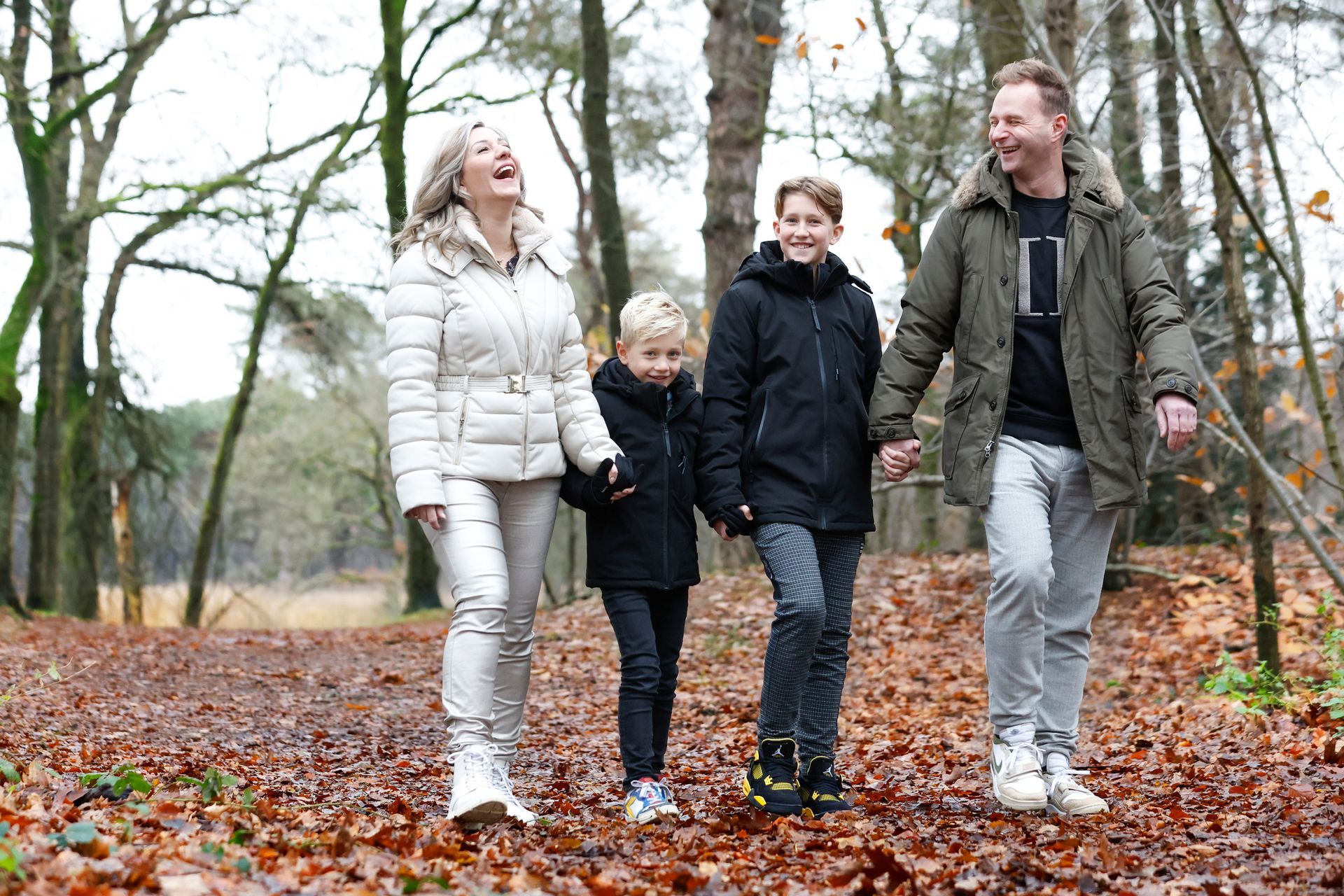 Een gezin loopt hand in hand door het bos.