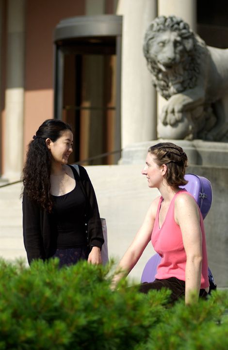 Two women are talking in front of a statue of a lion