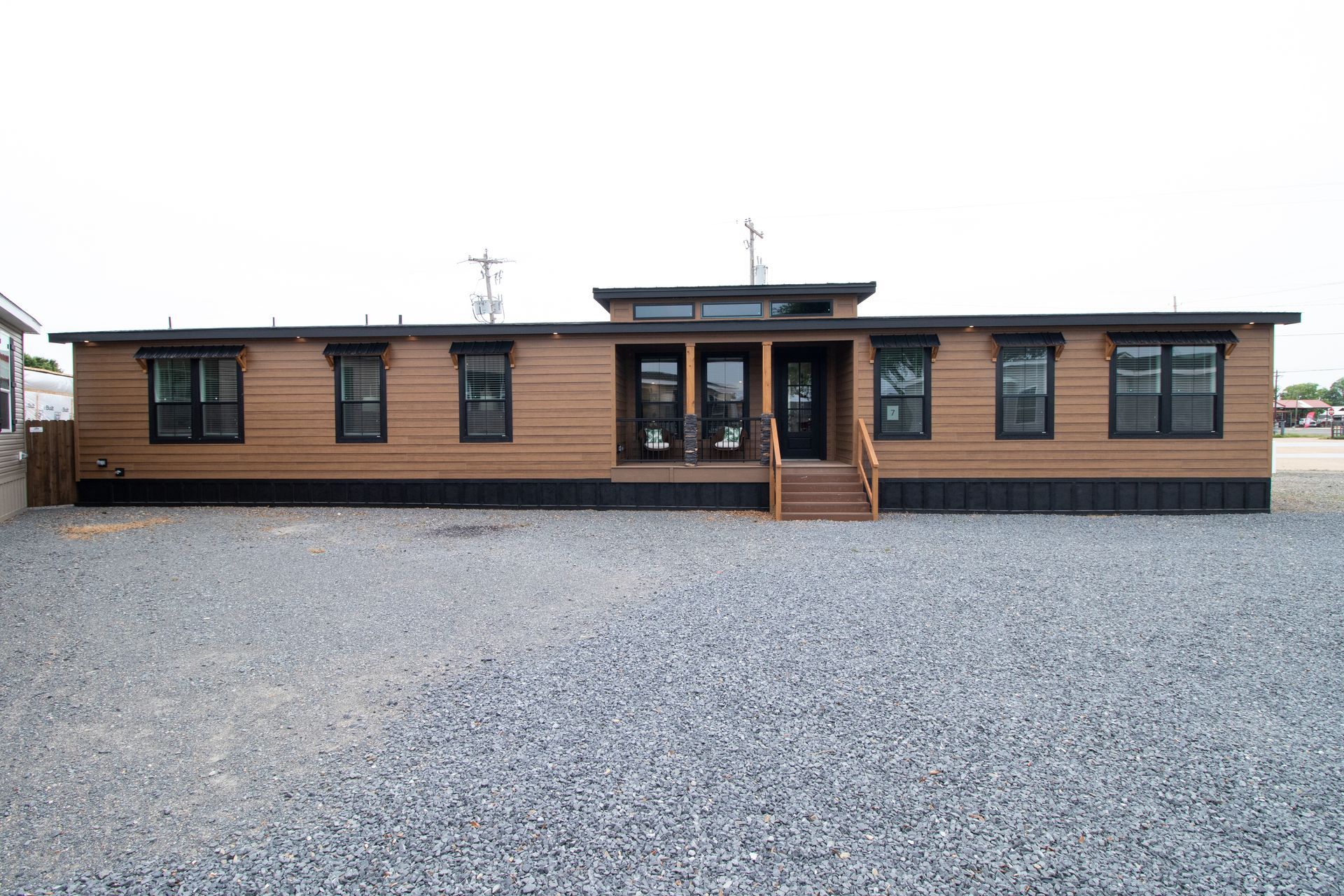 Single-story brown building with a central entrance and a wide gravel lot in front