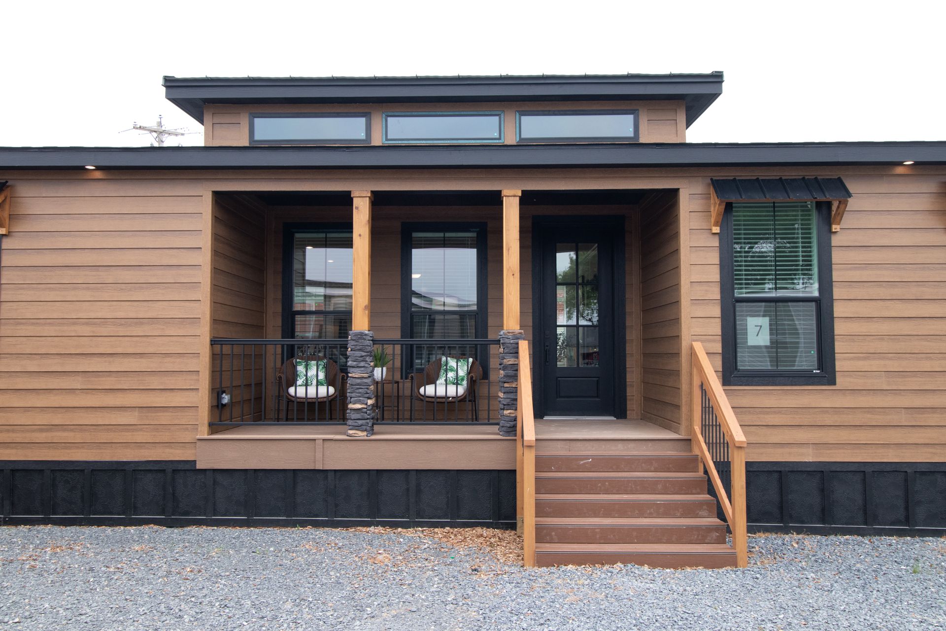 Modern single-story house with wood siding, front porch, and steps leading to the entrance