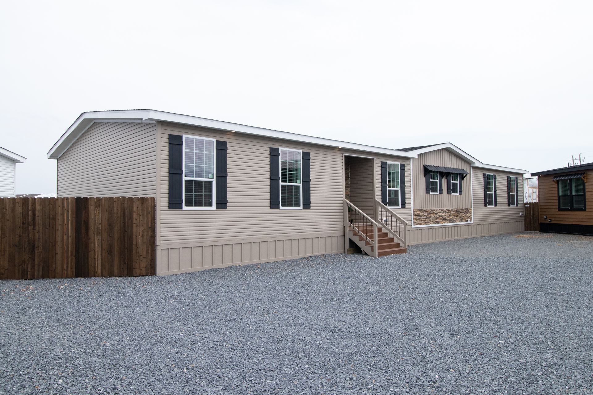 Beige mobile home with steps and gravel yard in a residential park