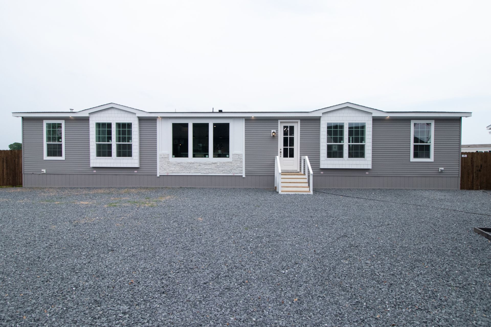 Single-story gray house with white trim and a large gravel driveway
