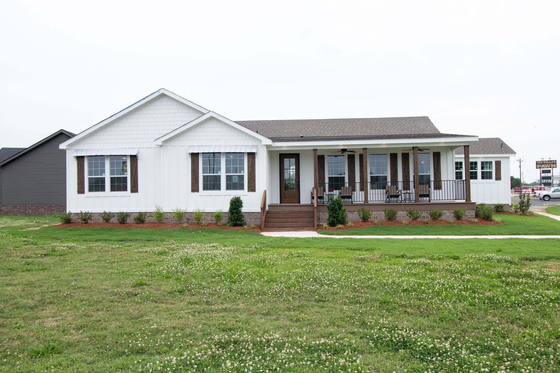 Single-story white house with gray roof, front porch, and a large green lawn.
