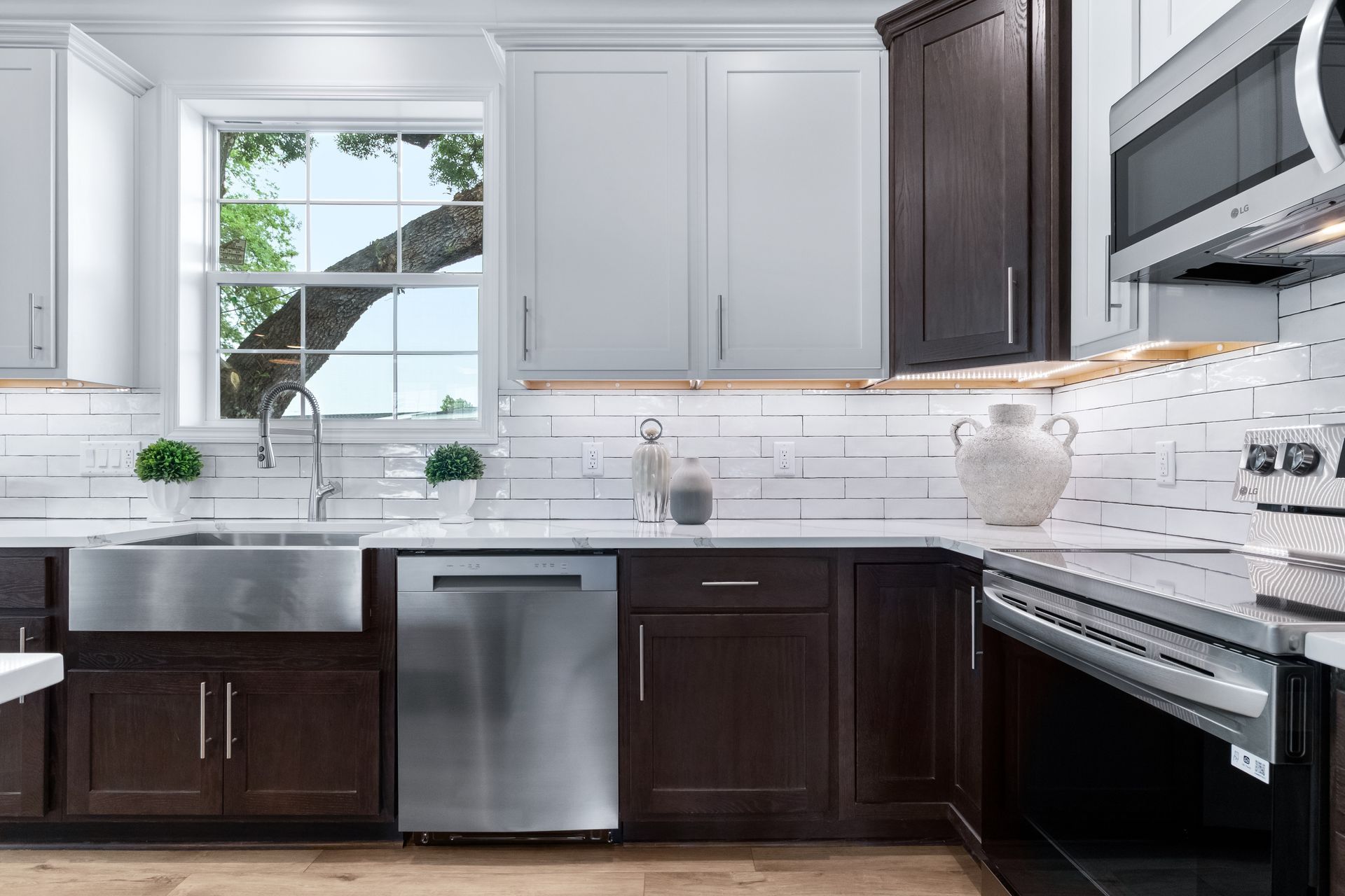 Modern white kitchen with dark cabinets, stainless steel appliances, and a window above the sink