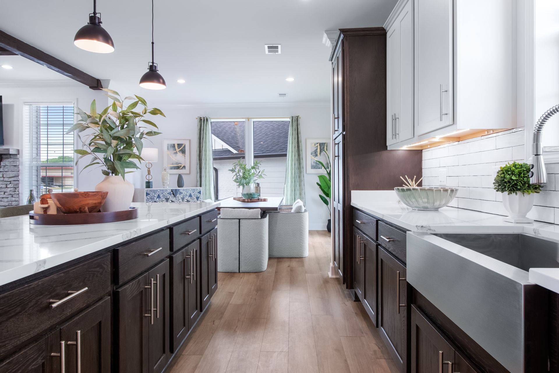 Modern kitchen with dark cabinets, white countertops, wood floors, and pendant lights