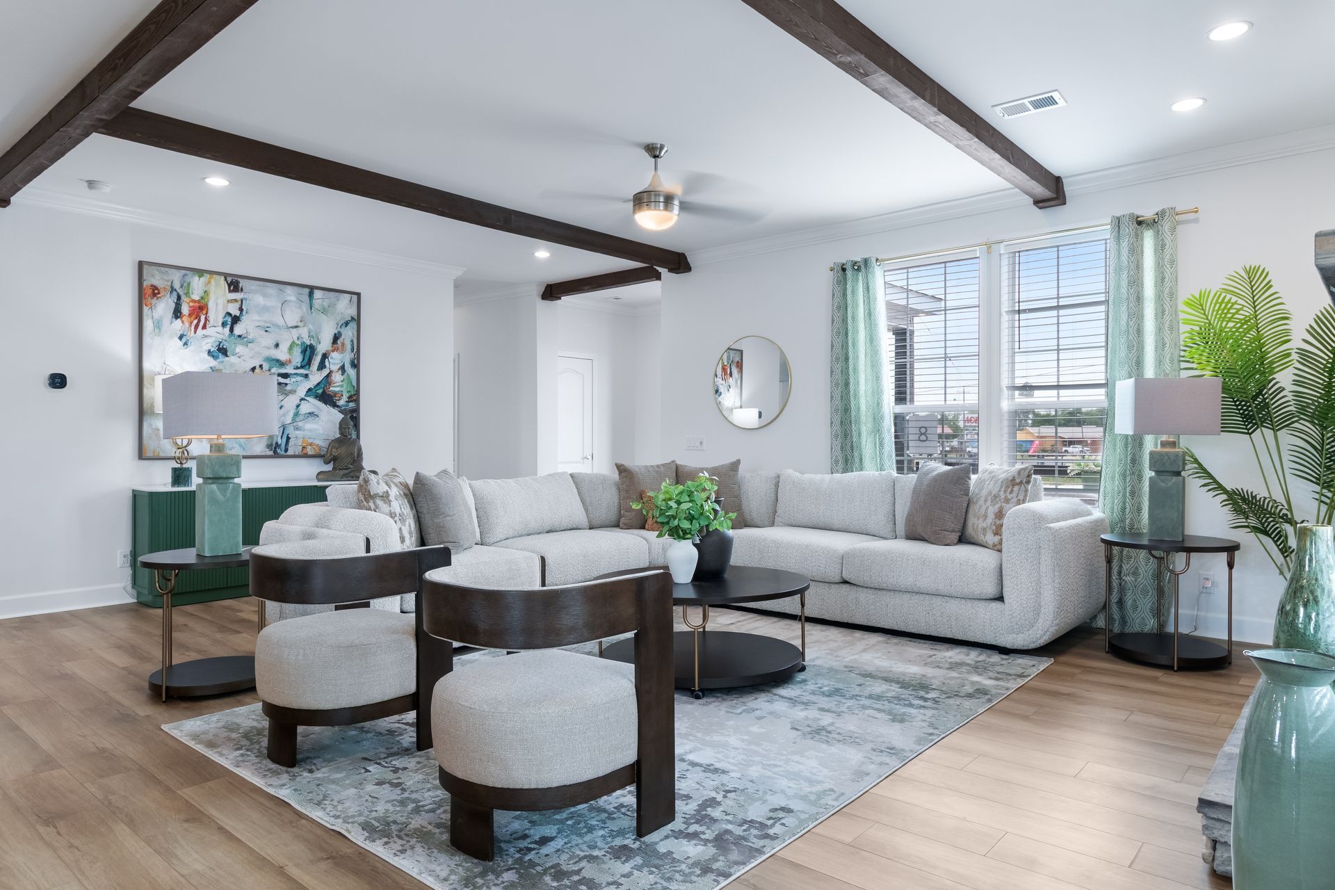 Bright modern living room with gray sectional, round coffee table, blue rug, and large windows
