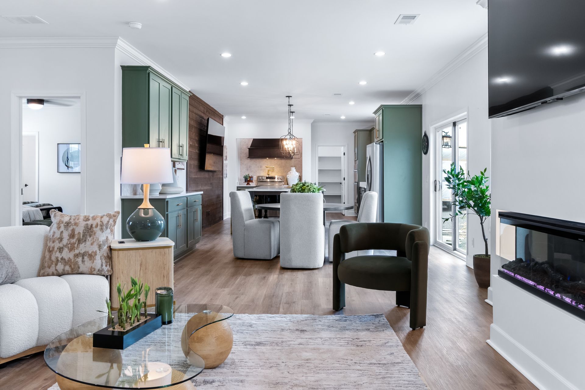 Bright open-concept living room and kitchen with white furniture, wood floors, and modern decor