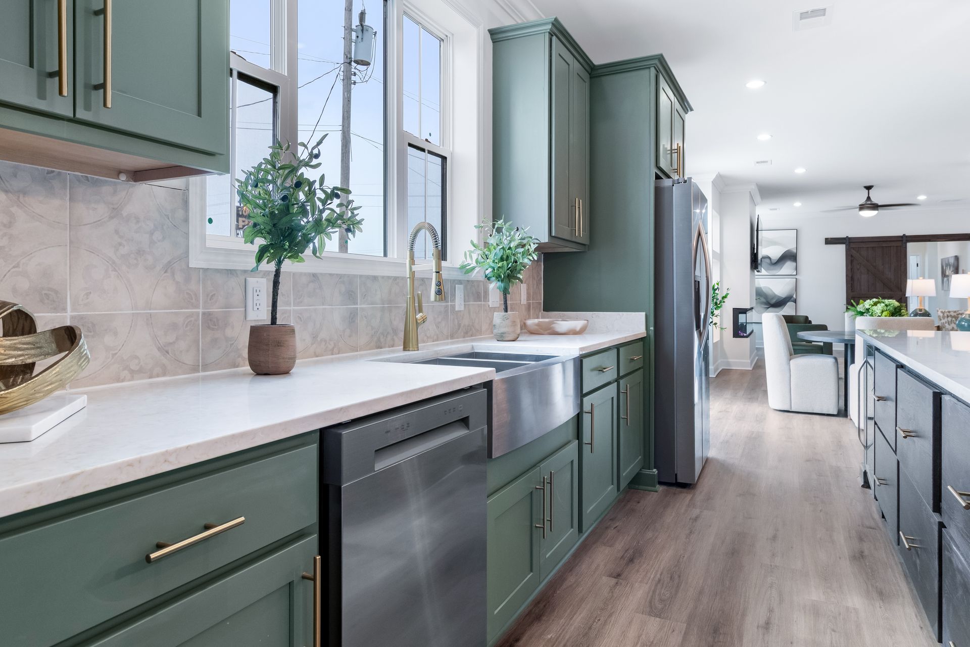 Modern kitchen with green cabinets, white countertops, and a long windowed sink area