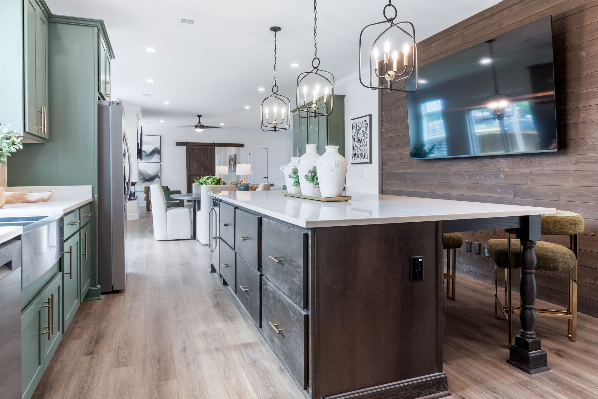 Modern kitchen with a large island, pendant lights, mint cabinets, and wall-mounted TV