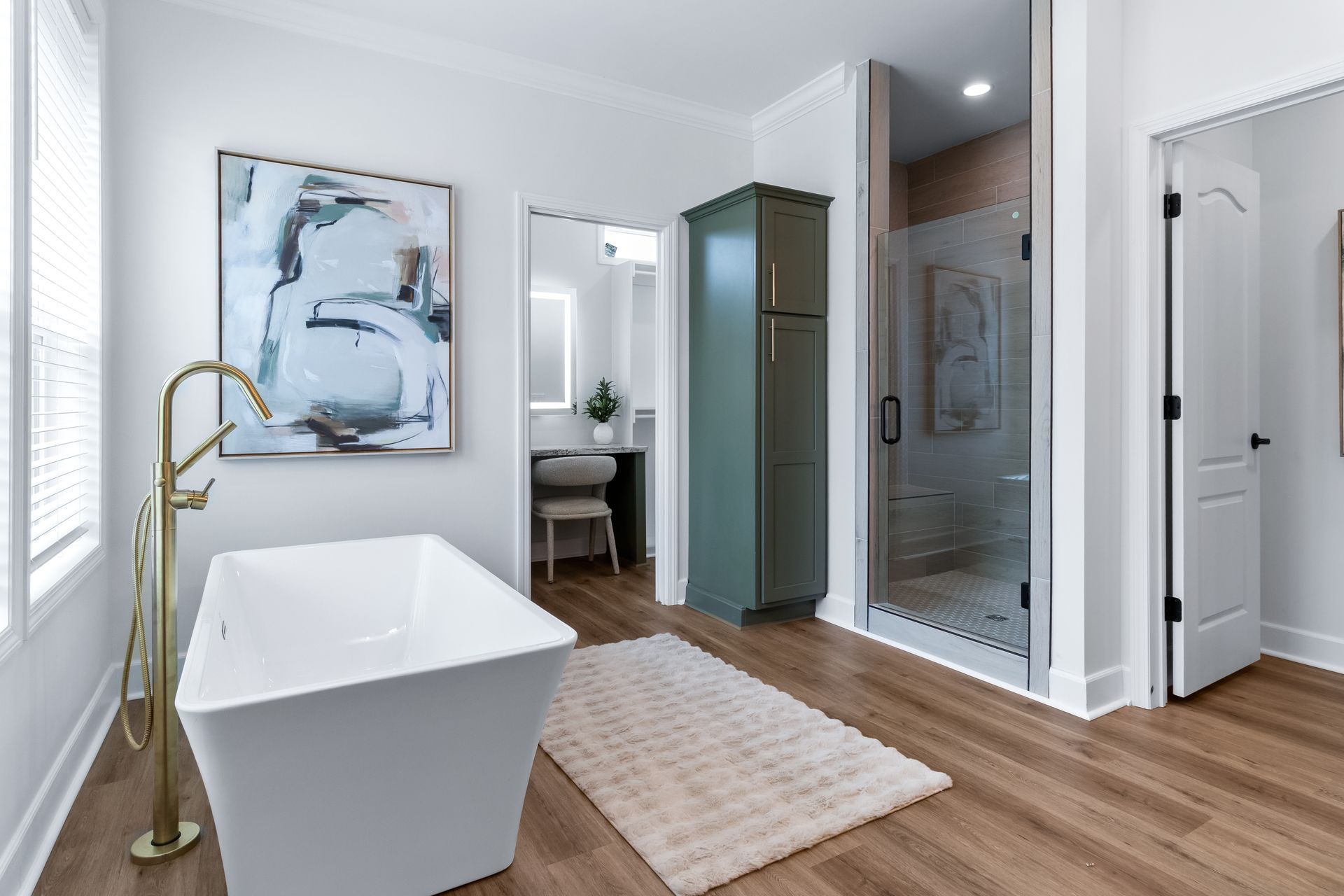Modern bathroom with freestanding tub, glass shower, double vanity, and wood floor