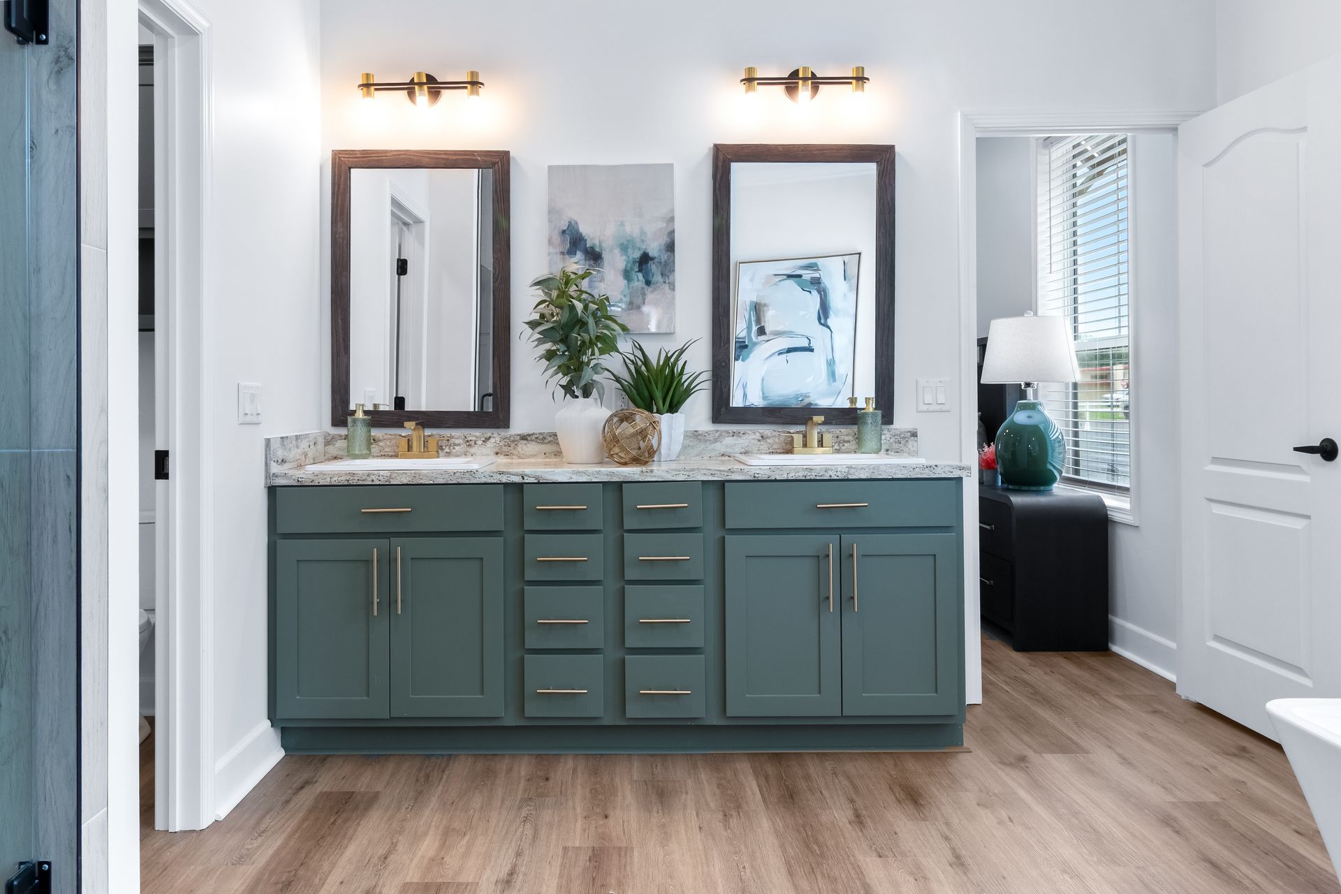 Modern bathroom vanity with green cabinets, dual mirrors, and white walls and doors.