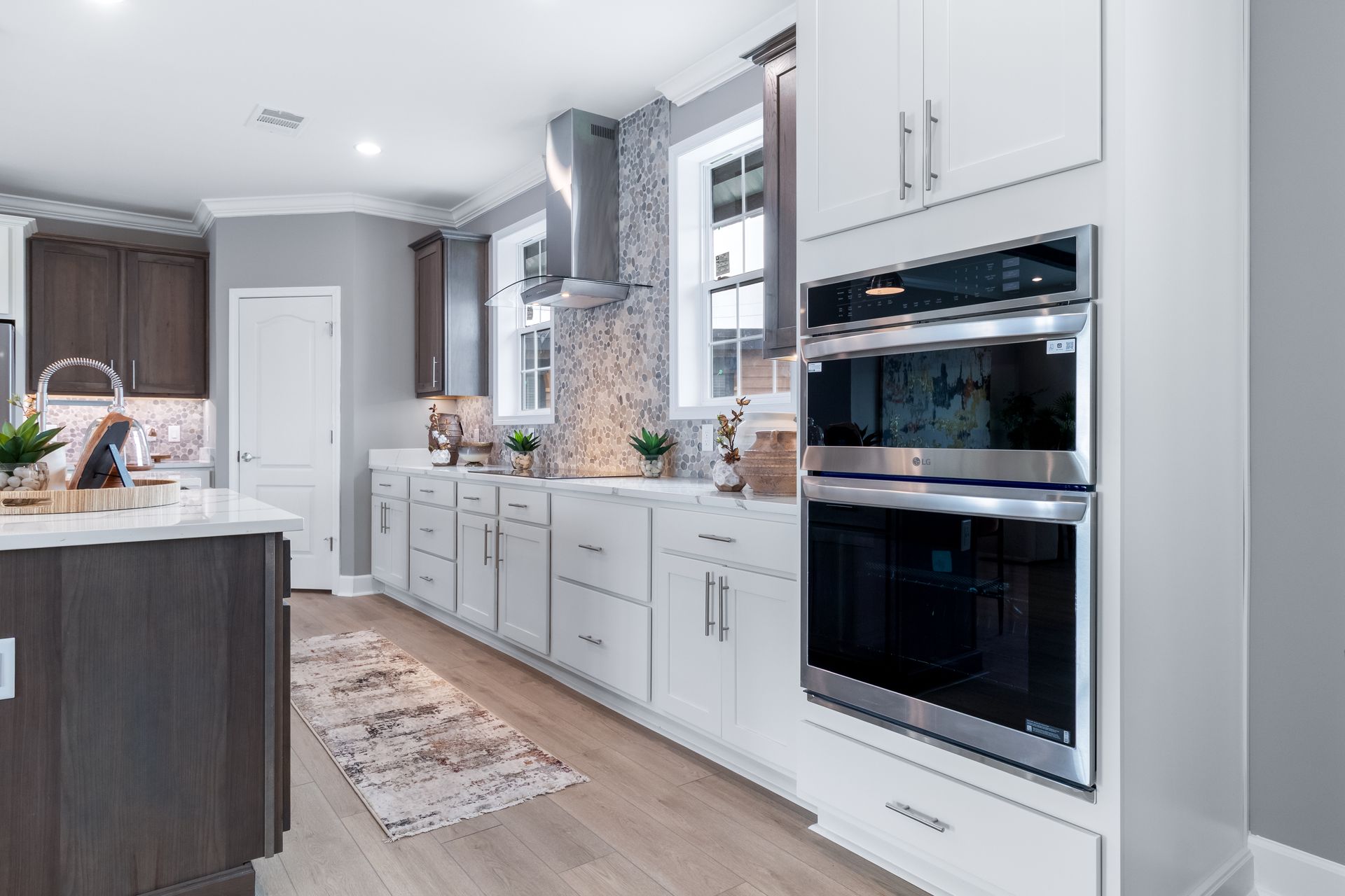 Modern white kitchen with built-in double oven, island, and large window