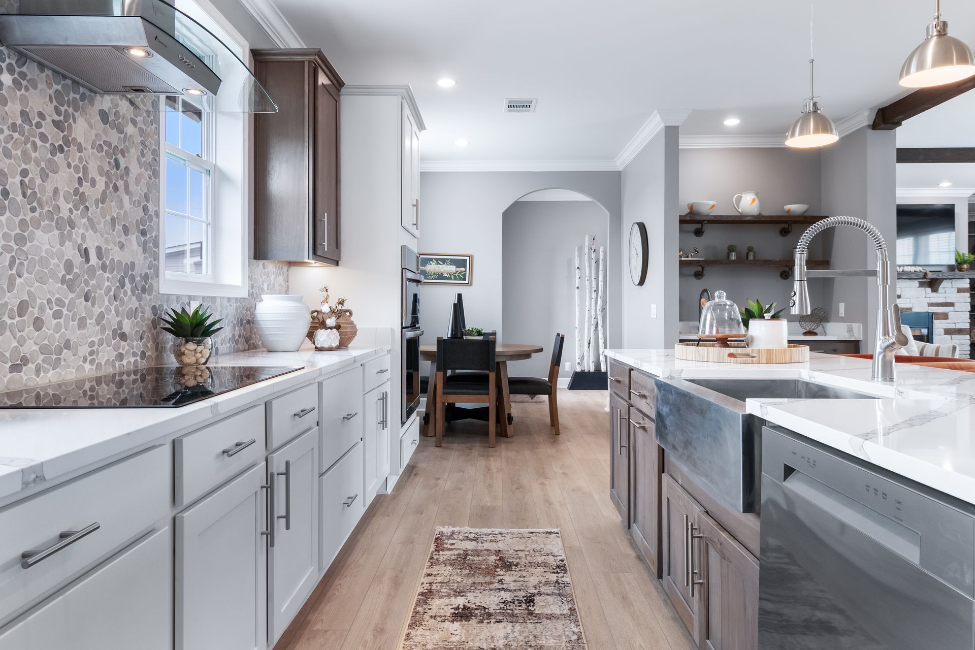 Modern kitchen with gray cabinets, white island, wood floors, and dining area in the background