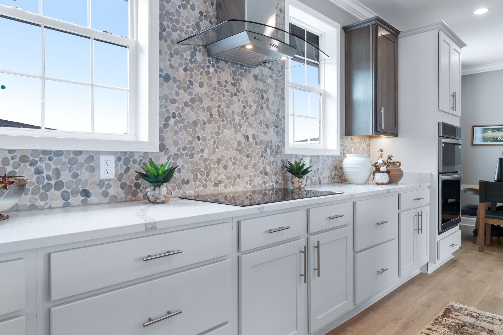 Bright modern kitchen with white cabinets, mosaic backsplash, and large windows