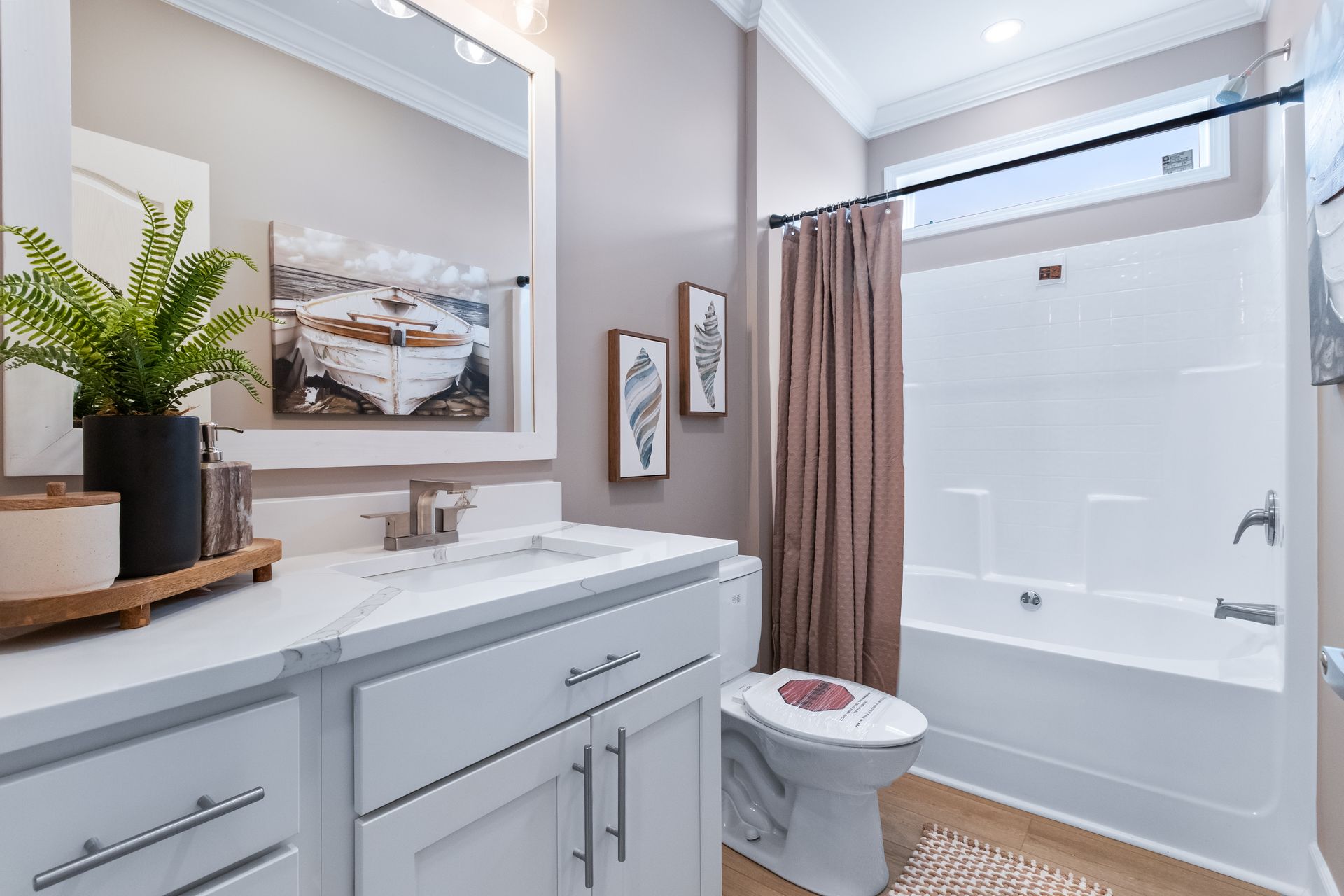 Bright modern bathroom with white vanity, mirror, toilet, and bathtub with beige shower curtain