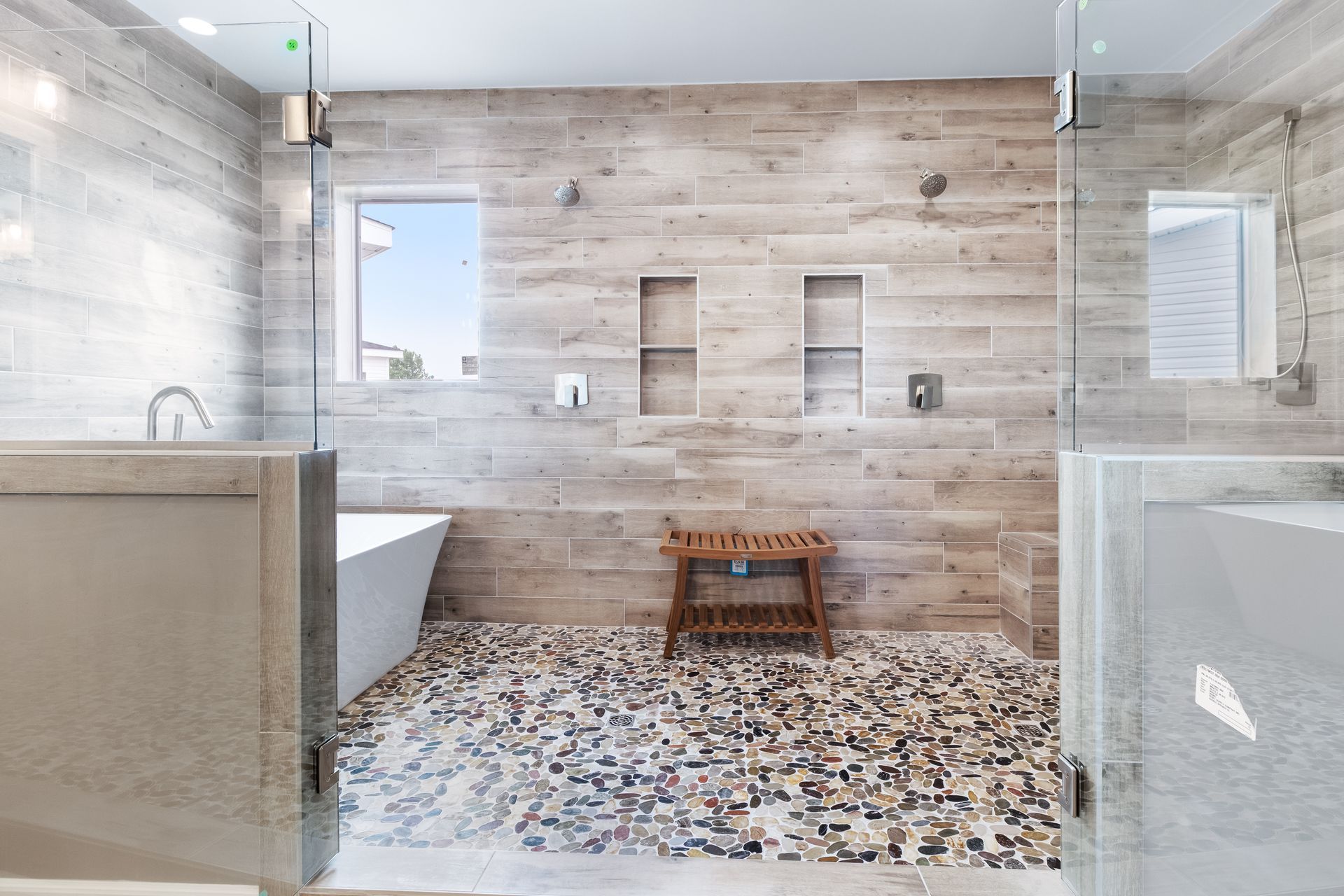 Modern bathroom with wood accent wall, mosaic floor, tub, sink, and glass shower enclosure
