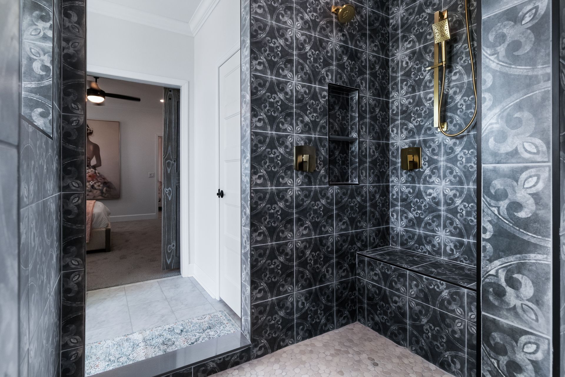 Black marble-tiled bathroom corner with a white-framed doorway and gold shower fixtures