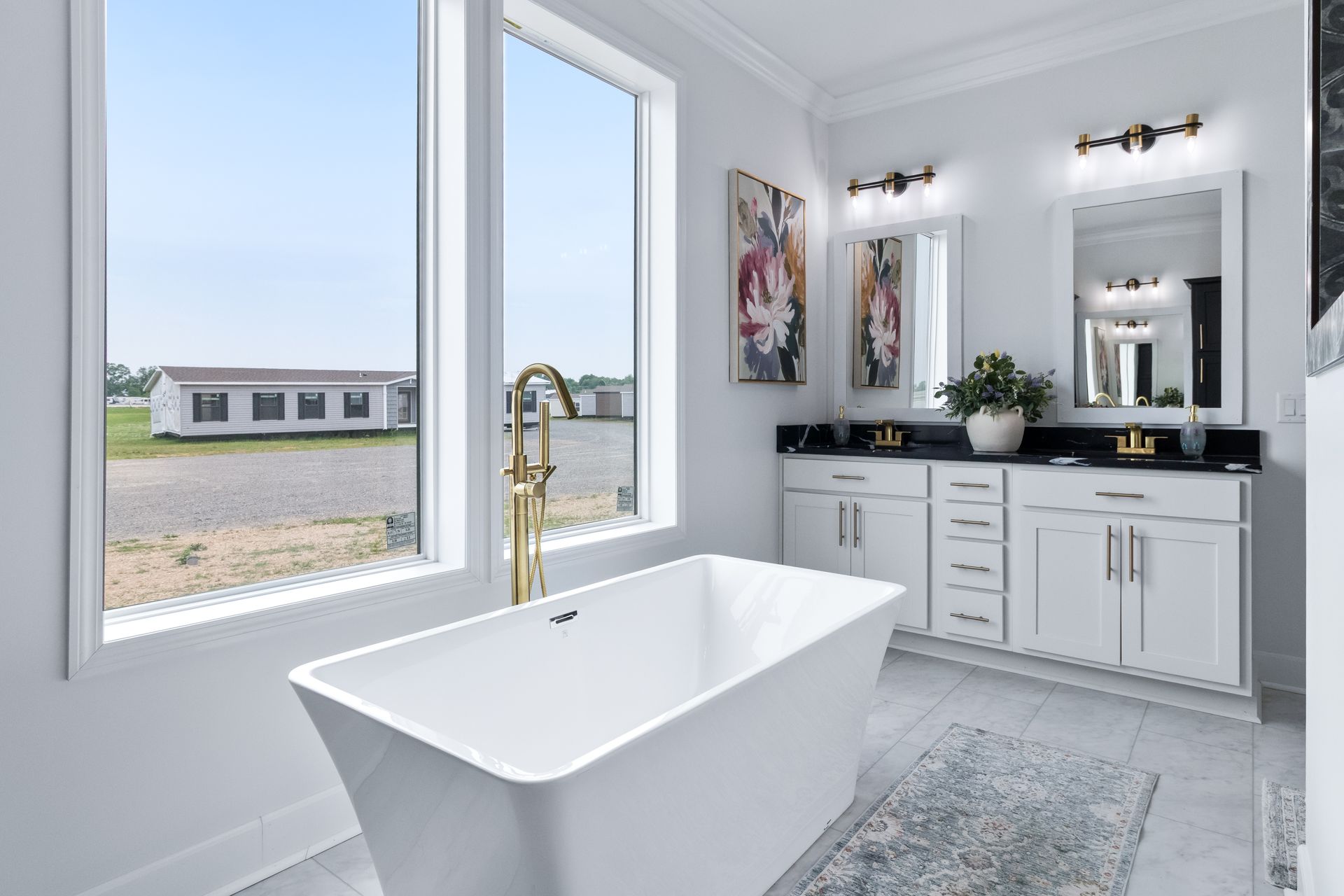 Bright modern bathroom with a freestanding tub, double vanity, and large windows overlooking a field