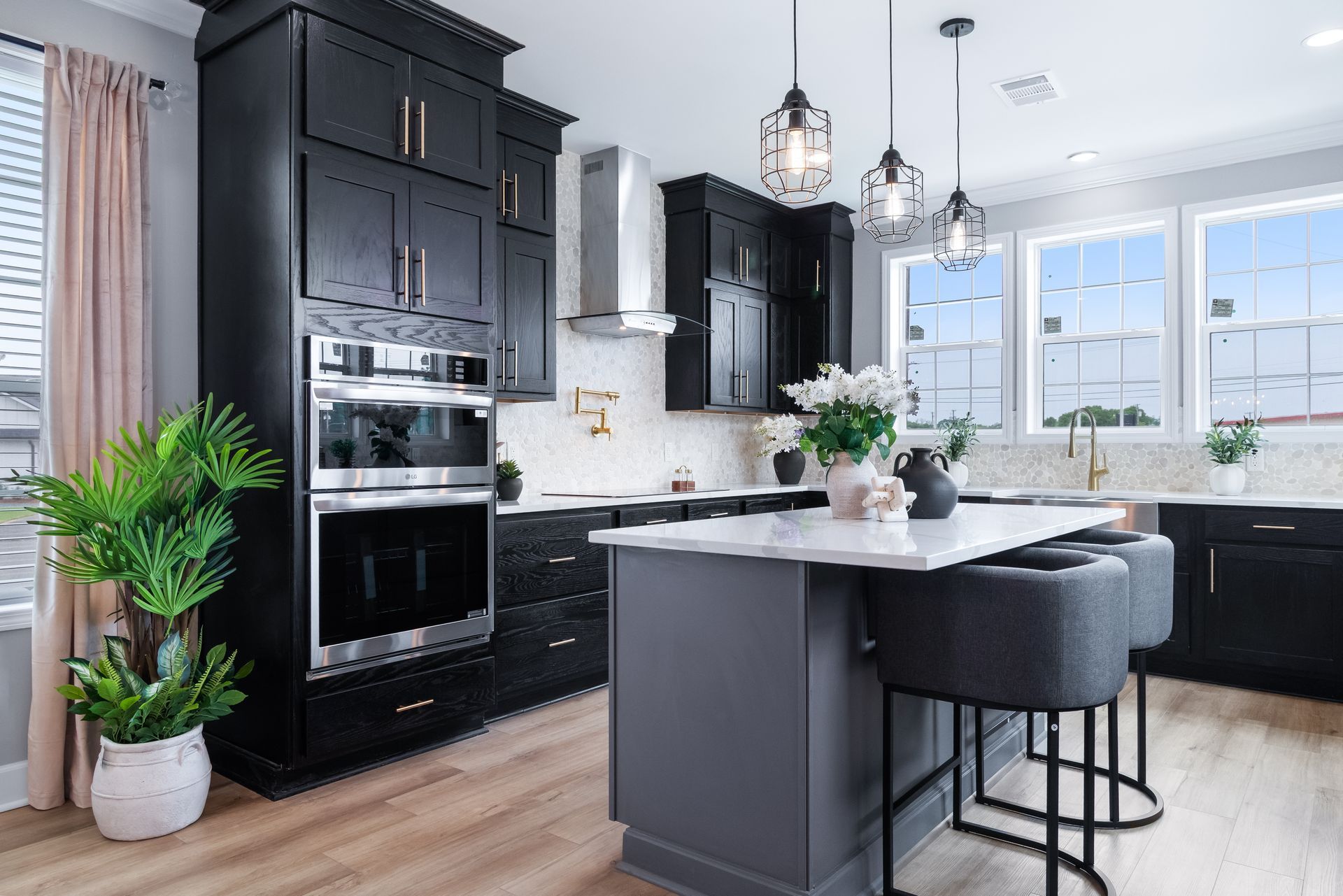 Modern black-and-white kitchen with island, bar stools, pendant lights, and large windows