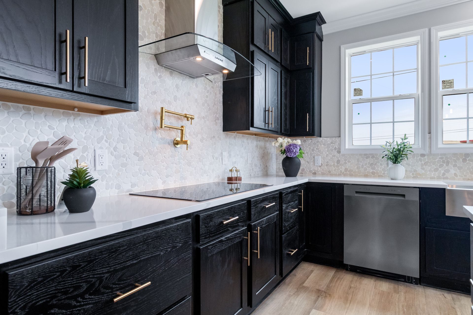 Modern kitchen with black cabinets, white countertops, and a window above the sink
