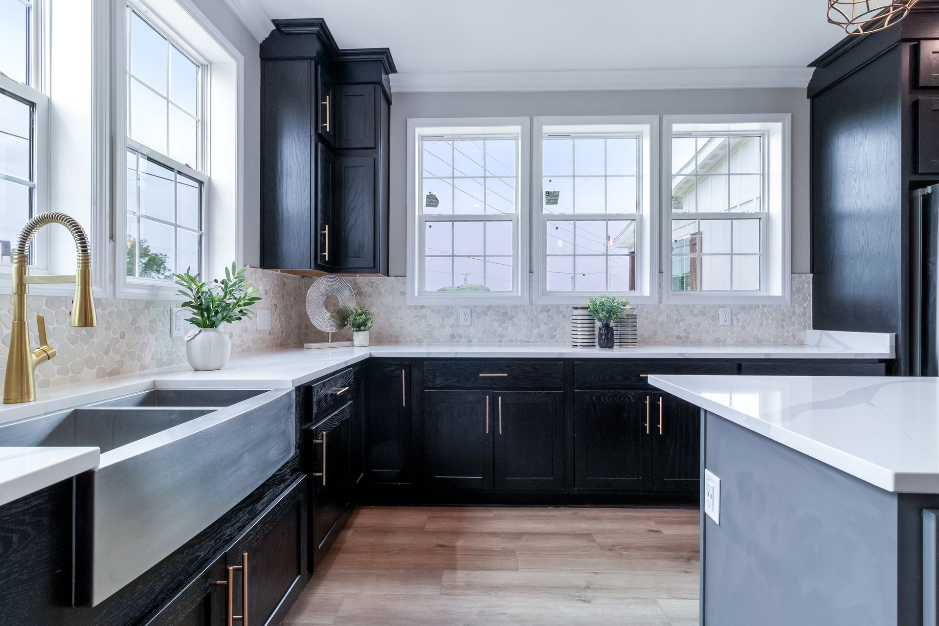 Modern kitchen with black cabinets, white countertops, and large windows letting in natural light