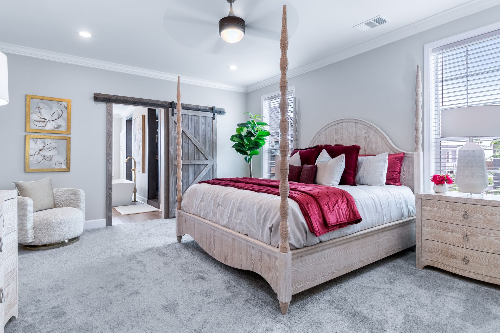 Bright, elegant bedroom with four-poster bed, white armchair, dresser, and soft gray carpet