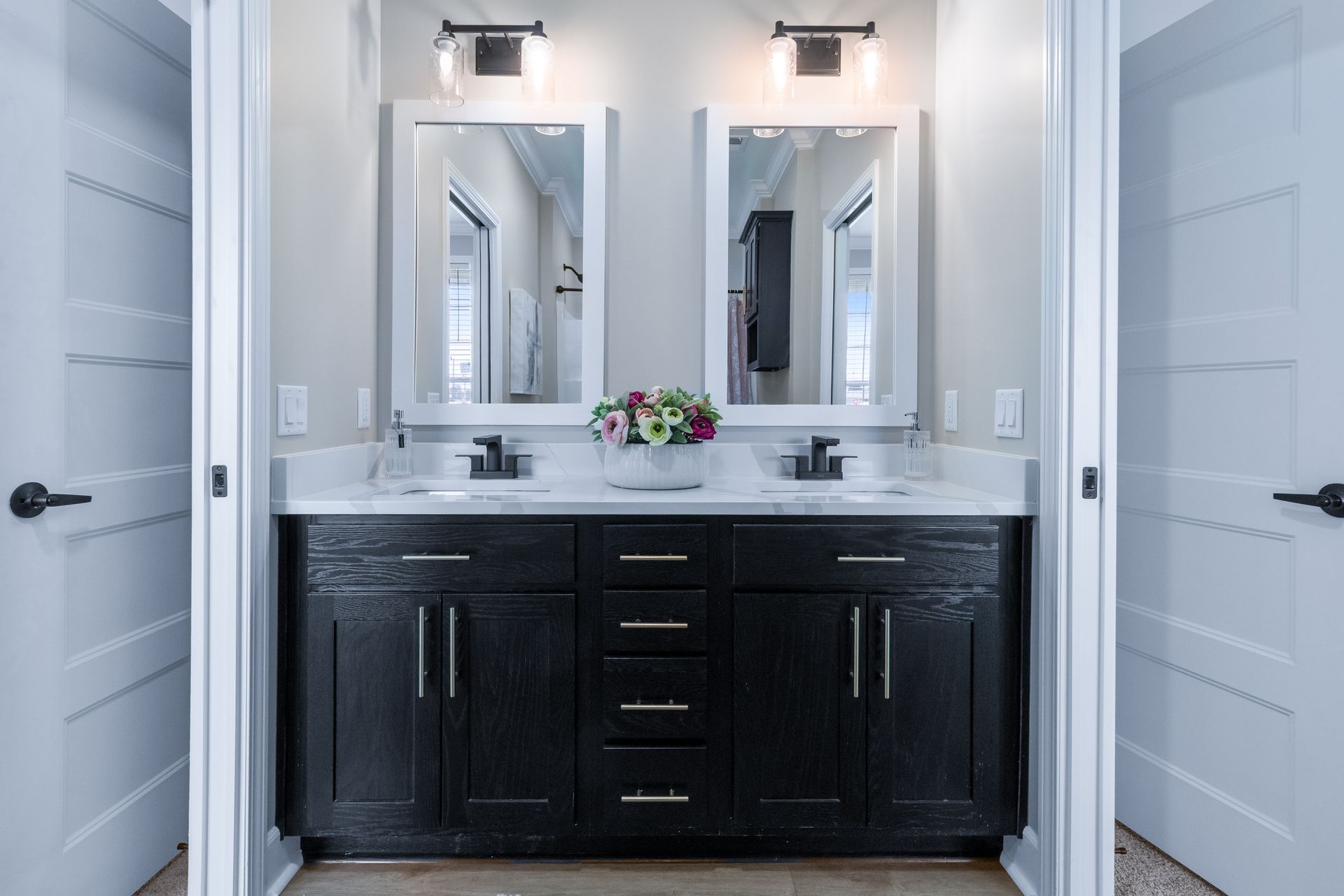 Double vanity bathroom with dark wood cabinets, twin mirrors, and white doors