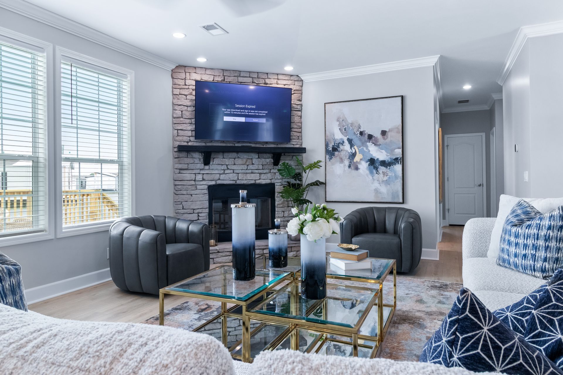 Modern living room with gray sofas, fireplace TV, large windows, and glass coffee table