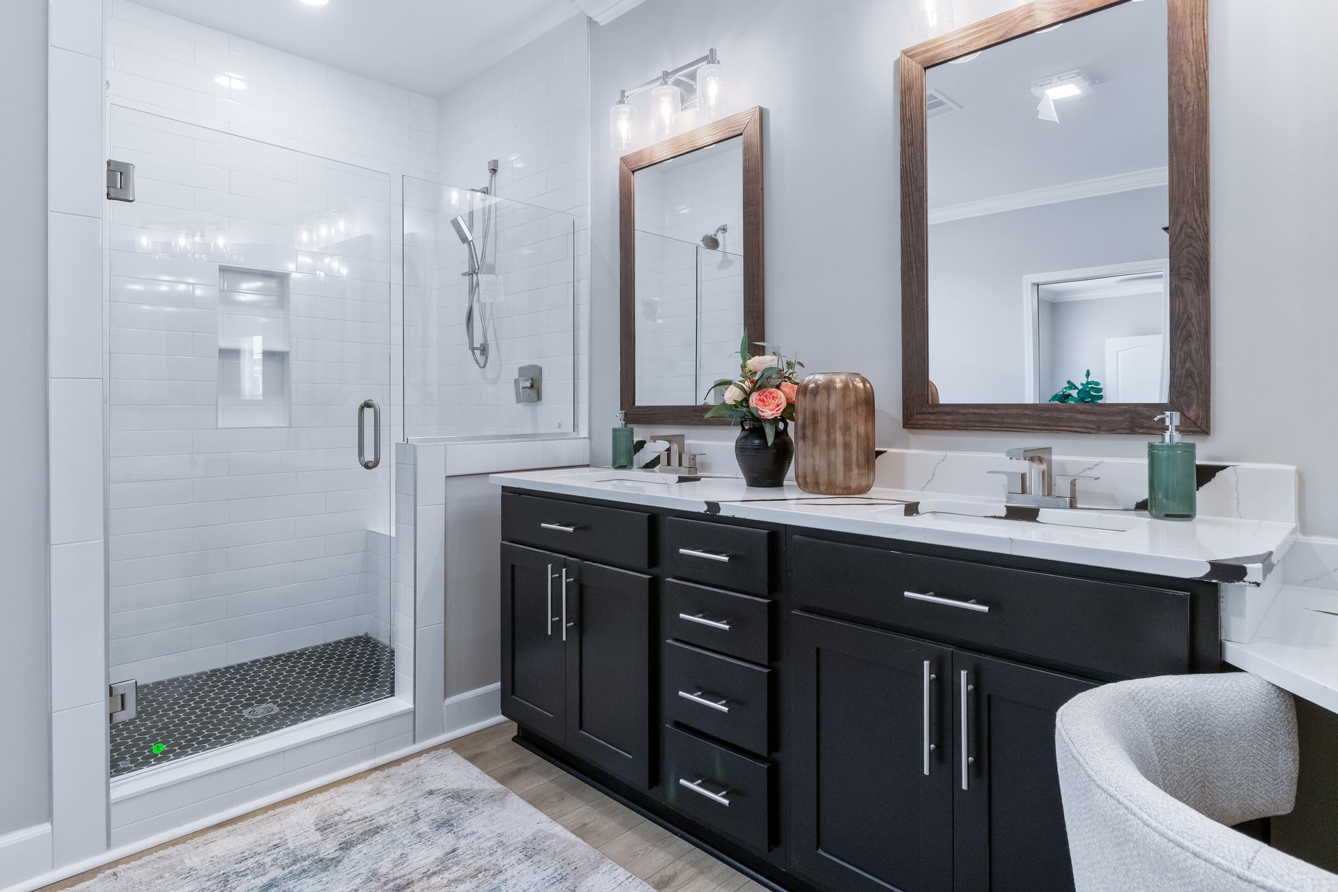 Modern bathroom with black vanity, white tiled shower, and large mirrors