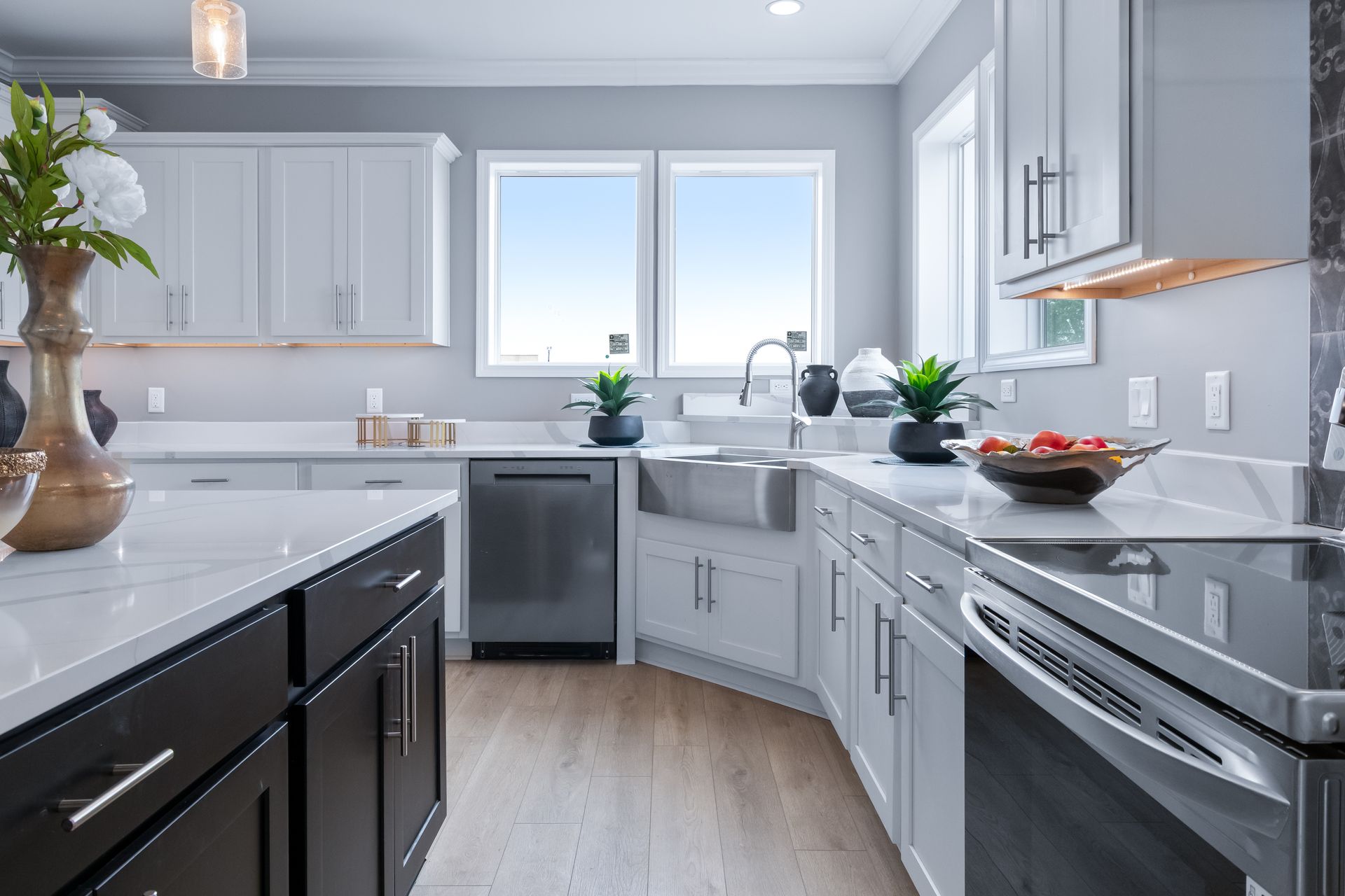 Bright modern kitchen with white cabinets, black counters, stainless appliances, and a large window over the sink