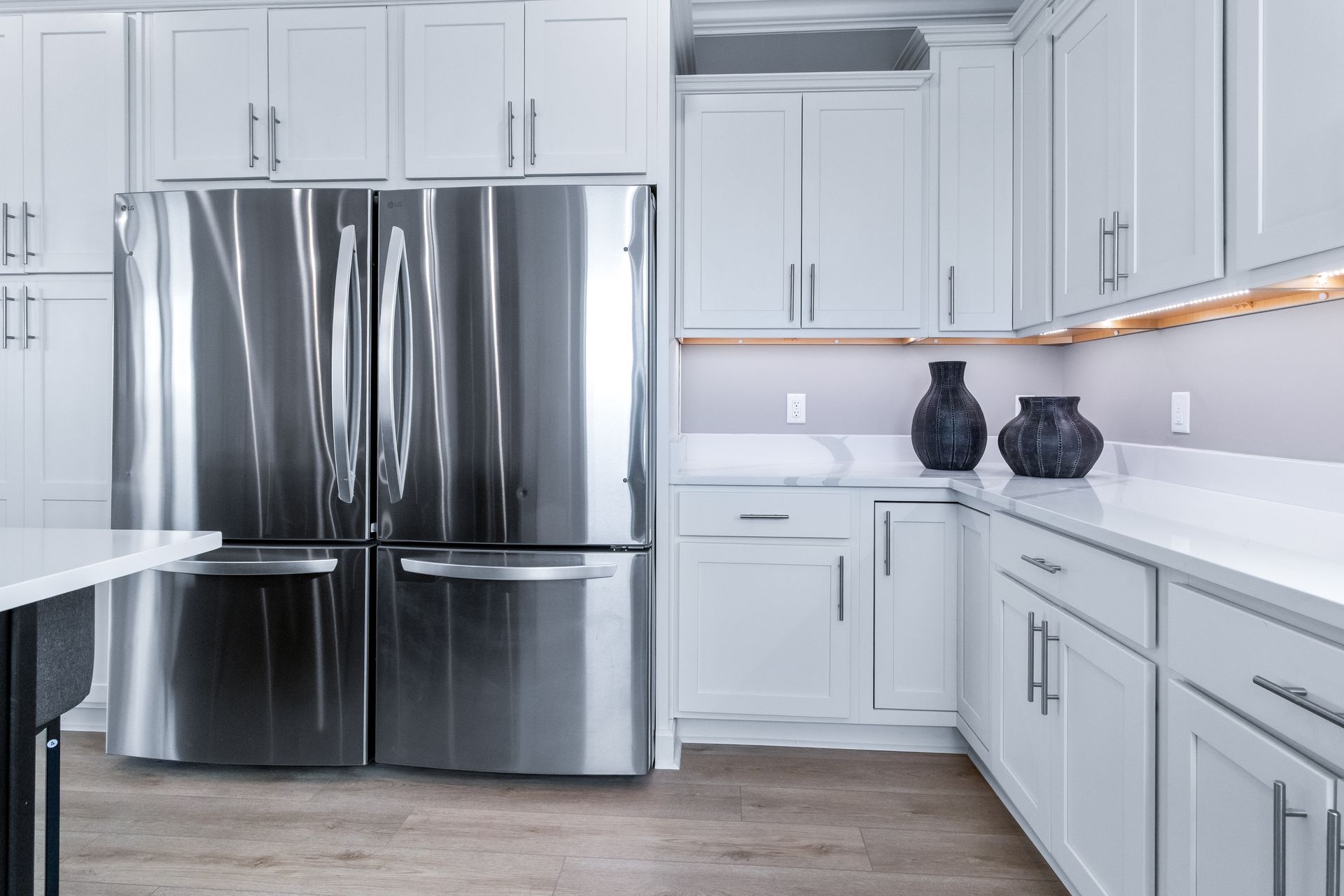 Modern white kitchen with stainless steel refrigerator and gray cabinets