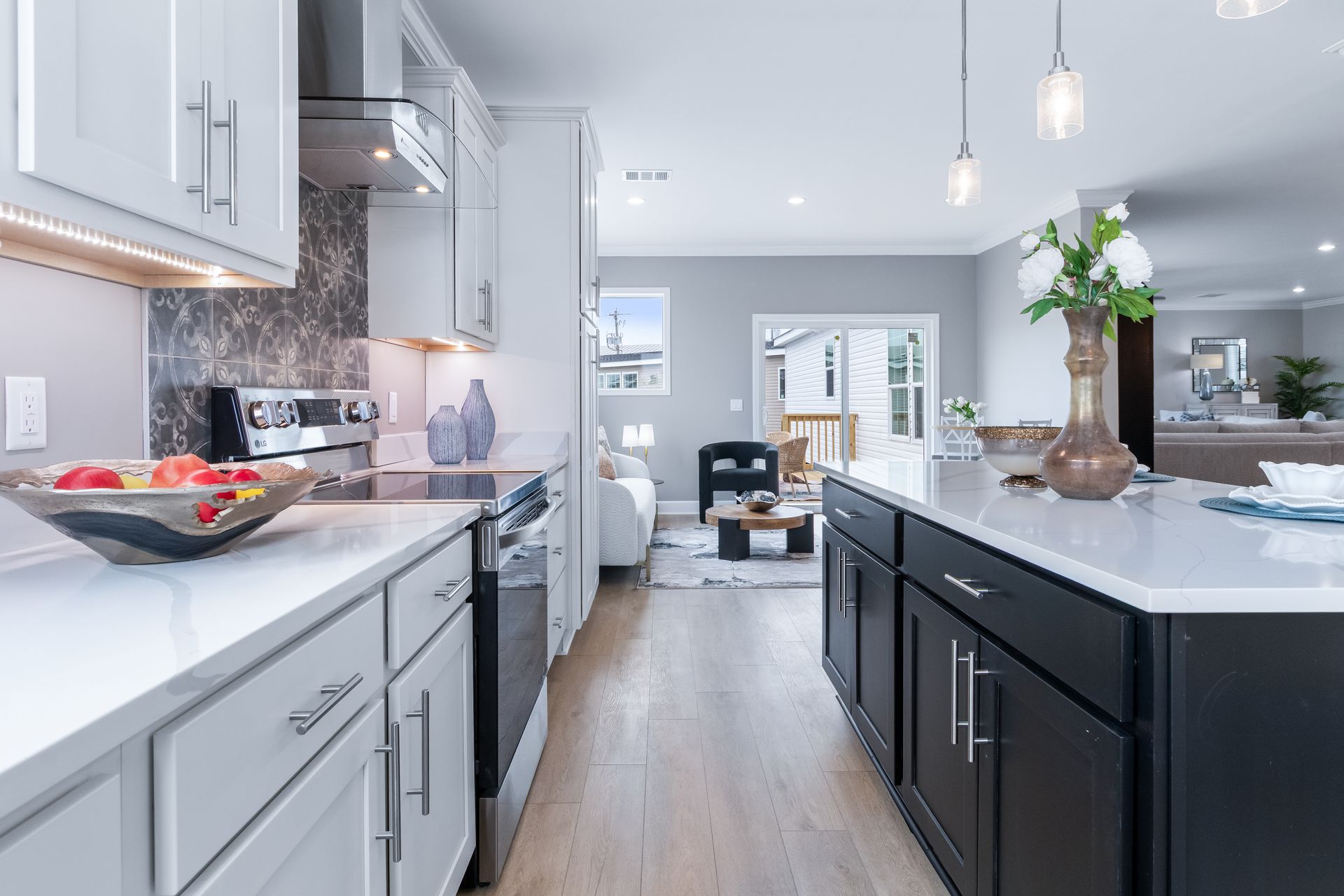 Modern kitchen with gray cabinets, black island, stainless appliances, and wood floors