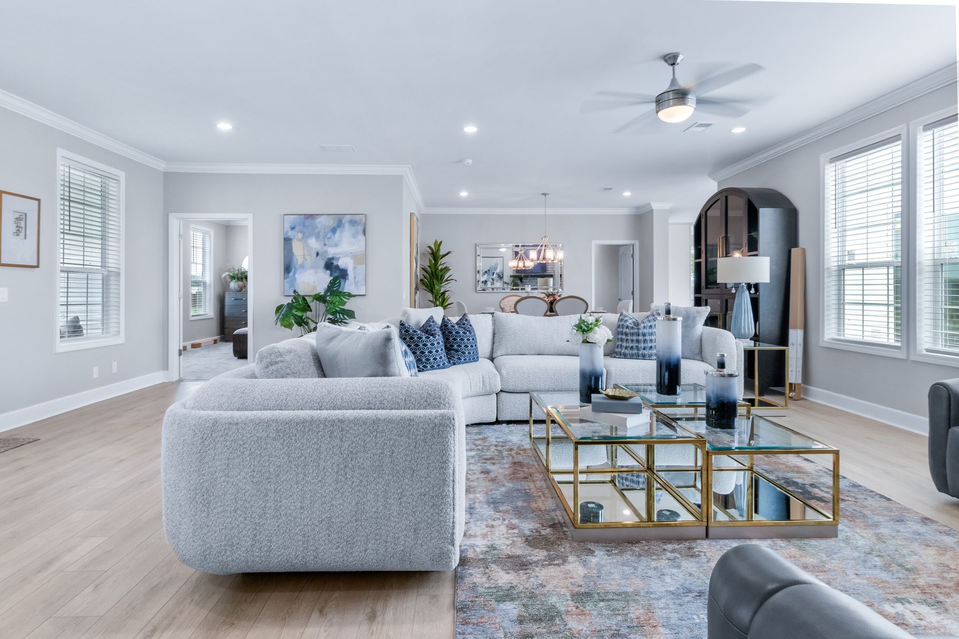Bright modern living room with gray sofas, blue accents, glass coffee table, and white walls