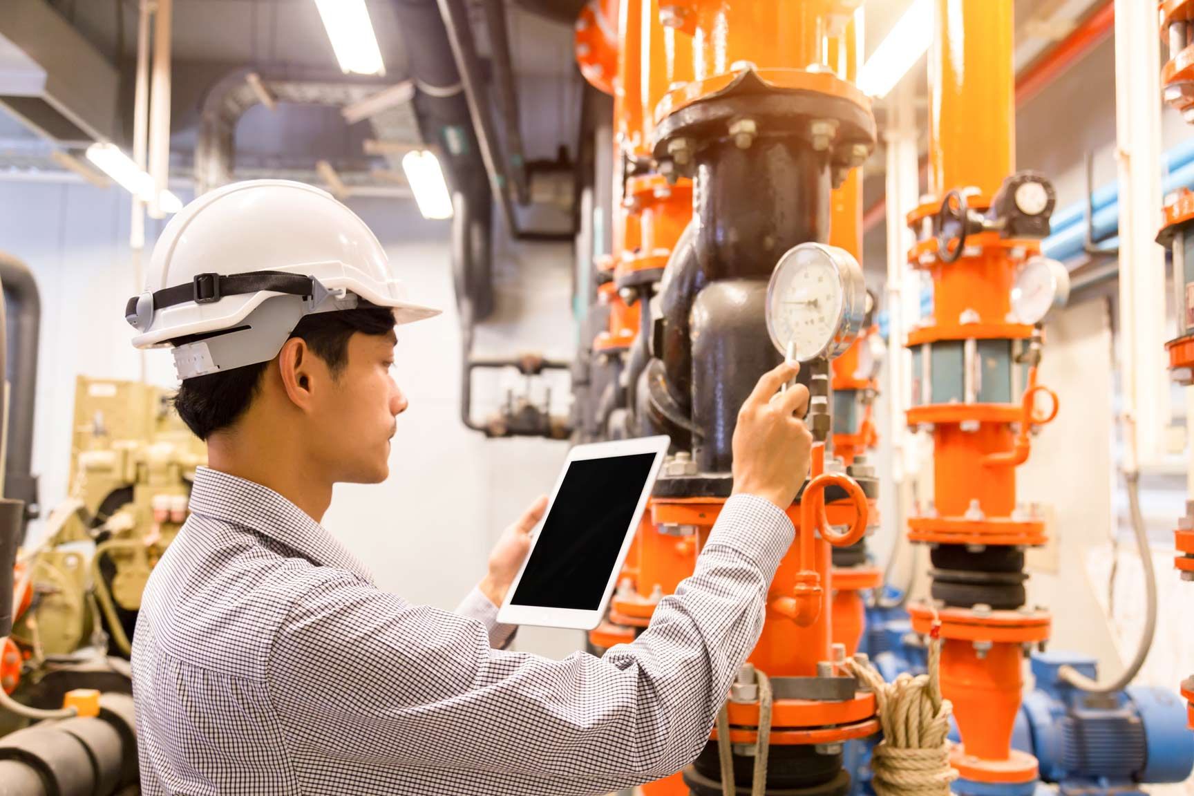 A technician performing maintenance and checking system data on a pressure gauge.