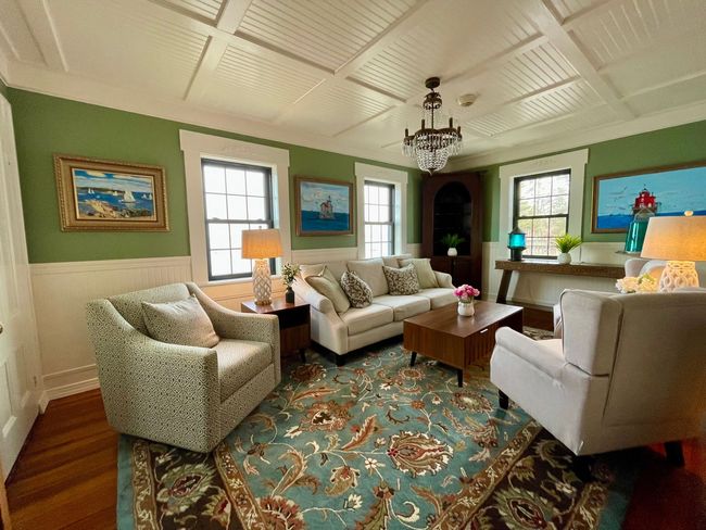 Cozy living room with cream sofas, teal rug, lamps, and framed art under a white paneled ceiling