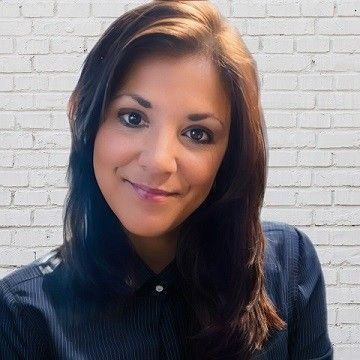 A man is holding a dog in his arms and the dog is wearing a sweater.