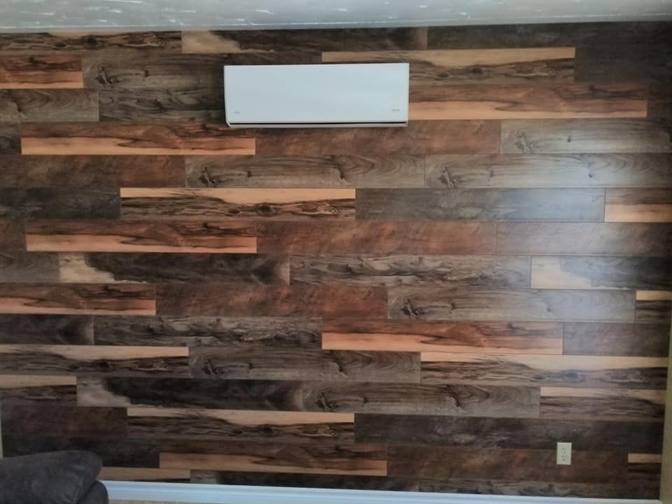 A wall covered in horizontal wood planks with varying shades of dark and light brown, featuring a white wall-mounted AC unit.