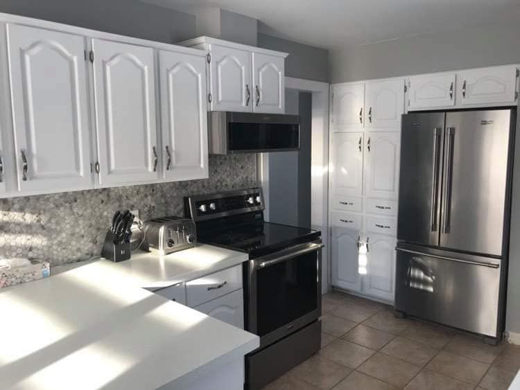 A kitchen with white cabinets, granite countertops, stainless steel appliances, and tile flooring.